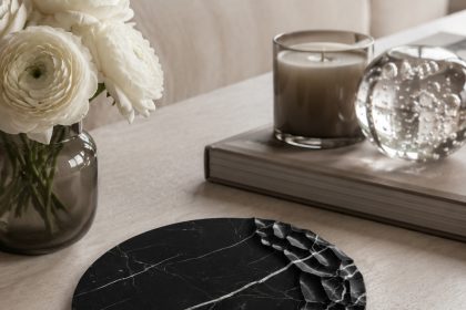 Chiseled-edge black marble tray as a sculptural centerpiece on a light wood coffee table with white flowers and candle