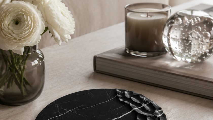 Chiseled-edge black marble tray as a sculptural centerpiece on a light wood coffee table with white flowers and candle