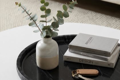 Round black marble tray on white coffee table styled with vase, books and keys