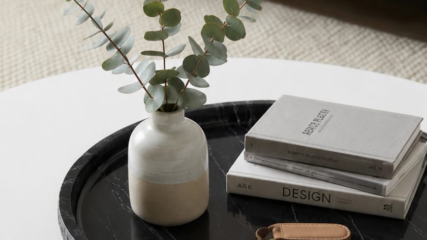 Round black marble tray on white coffee table styled with vase, books and keys