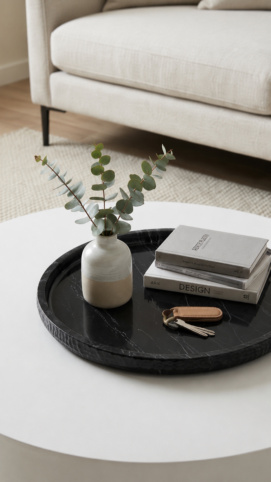 Round black marble tray on white coffee table styled with vase, books and keys