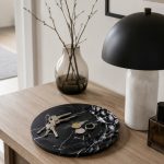 Sculpted relief Nero Marquina marble dish with organic carved surface pattern in entryway setting