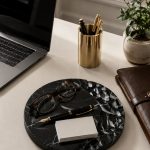 Artisanal marble jewelry tray with sculpted surface on light oak console table with modern lamp