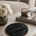 Wabi-sabi style carved Nero Marquina dish on wooden bedside table with linen bedding and morning light